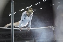 Ginnasta femminile che si esibisce su barre irregolari in arena — Foto stock