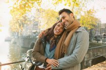 Riendo pareja joven abrazándose en el puente de otoño sobre el canal en Amsterdam - foto de stock