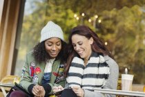 Усміхнені молоді жінки друзі пишуть листівку в міському тротуарному кафе — стокове фото