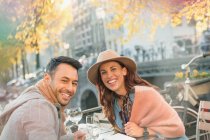 Portrait smiling young couple at urban autumn sidewalk cafe — Stock Photo