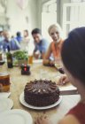 Mulher corte bolo de aniversário de chocolate com amigos na mesa do restaurante — Fotografia de Stock