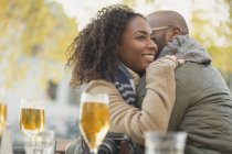 Smiling couple hugging and drinking beer at sidewalk cafe — Stock Photo