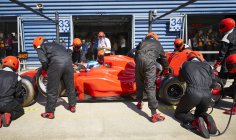 Tripulación de pozos reemplazando neumáticos en un coche de fórmula de carrera en pit lane - foto de stock