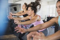 Energetic young women riding elliptical bikes in exercise class — Stock Photo