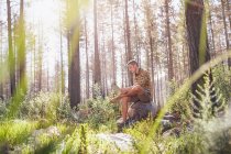 Молодий чоловік використовує цифровий планшет у сонячному лісі — стокове фото