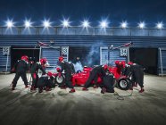 Pit crew working on formula one race car in pit stop — Stock Photo