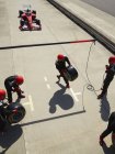 Tripulação do poço preparando pneus para se aproximar de fórmula um carro de corrida em pit lane — Fotografia de Stock
