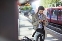 Бізнесмен використовує мобільний телефон на залізничній станції — стокове фото