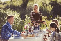 Mother serving food to family at garden party patio table — Stock Photo