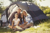 Портрет улыбающаяся семья отдыхает снаружи солнечной палатки кемпинга — стоковое фото