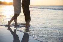 Piernas de pareja joven de pie en la playa - foto de stock