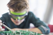 Focused boy student soldering circuit board in classroom — Stock Photo