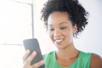 Портрет жінки з чорним кучерявим волоссям, що тримає мобільний телефон — стокове фото