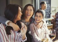 Entusiástico, mulheres sorridentes amigos abraçando e bebendo no bar — Fotografia de Stock