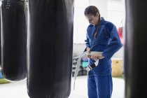Young woman tying judo belt at punching bags in gym — Stock Photo