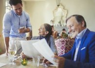 Kellner nimmt Bestellung von Seniorpaar mit Menüs am Restauranttisch entgegen — Stockfoto