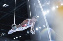 Gymnaste masculin effectuant sur les anneaux de gymnastique dans l'arène — Photo de stock