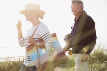 Älteres Paar spaziert in sonnigem Strandgras — Stockfoto