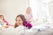 Lachende Schwestern, die zu Hause im Bett spielen — Stockfoto