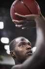 Primer plano enfocado joven jugador de baloncesto masculino disparando la pelota - foto de stock