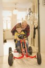 Pai empurrando filho em carro de brinquedo no corredor do foyer — Fotografia de Stock