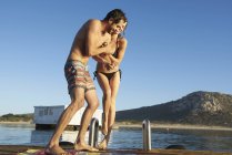 Beautiful young couple in swimming suits at water — Stock Photo