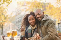 Ritratto sorridente giovane coppia abbracciare e bere birra al caffè marciapiede autunno — Foto stock