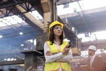 Female steel worker with walkie-talkie in factory — Stock Photo