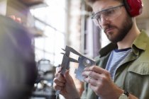 Male designer using calipers in workshop — Stock Photo