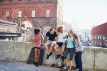 Friends with skateboards hanging out on urban summer wall — Stock Photo