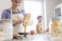 Mulheres caterers cozimento, derramando massa bolo em lata na cozinha — Fotografia de Stock