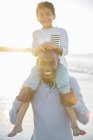 Portrait of father carrying son on shoulders and smiling — Stock Photo