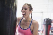 Rire jeune boxeuse au sac de boxe dans la salle de gym — Photo de stock