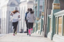 Läufer laufen auf sonnigem Bürgersteig — Stockfoto