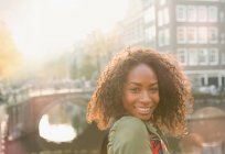 Portrait smiling young woman along urban canal, Amsterdam — Stock Photo