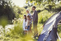 Familie auf sonnigem Campingplatz am Seeufer schaut weg — Stockfoto