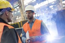 Steel workers talking in factory to each other — Stock Photo