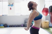Vue latérale de femme étirant la poitrine dans la salle de gym — Photo de stock