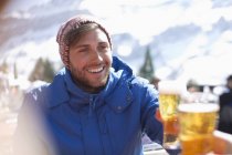 Uomo sorridente in abbigliamento caldo bere birra all'aperto — Foto stock