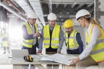 Engineers reviewing blueprints at construction site — Stock Photo