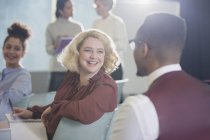 Lächelnde Geschäftsfrau dreht sich um und hört Geschäftsmann im Konferenzpublikum zu — Stockfoto