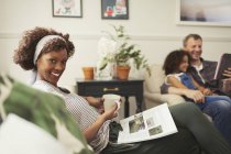 Портрет усміхненої жінки, що розслабляється з чаєм і журналом на дивані — стокове фото