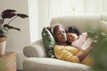 Serena mãe e filha cochilando e abraçando no sofá — Fotografia de Stock