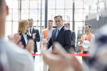 Smiling businessman and businesswoman cutting ribbon at new construction site ceremony — Stock Photo
