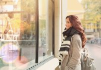 Sorridente giovane donna vetrina al negozio urbano — Foto stock