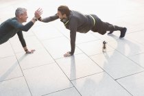 Men doing plank exercises and high-fiving — Stock Photo