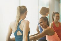 Women talking and stretching at barre in exercise class gym studio — Stock Photo