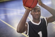 Сосредоточенный молодой баскетболист бросает мяч на корте — стоковое фото