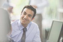 Homme d'affaires attentif et souriant à l'écoute d'un collègue lors d'une réunion — Photo de stock