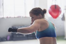 Решительная женщина-боксер теневой бокс в тренажерном зале — стоковое фото